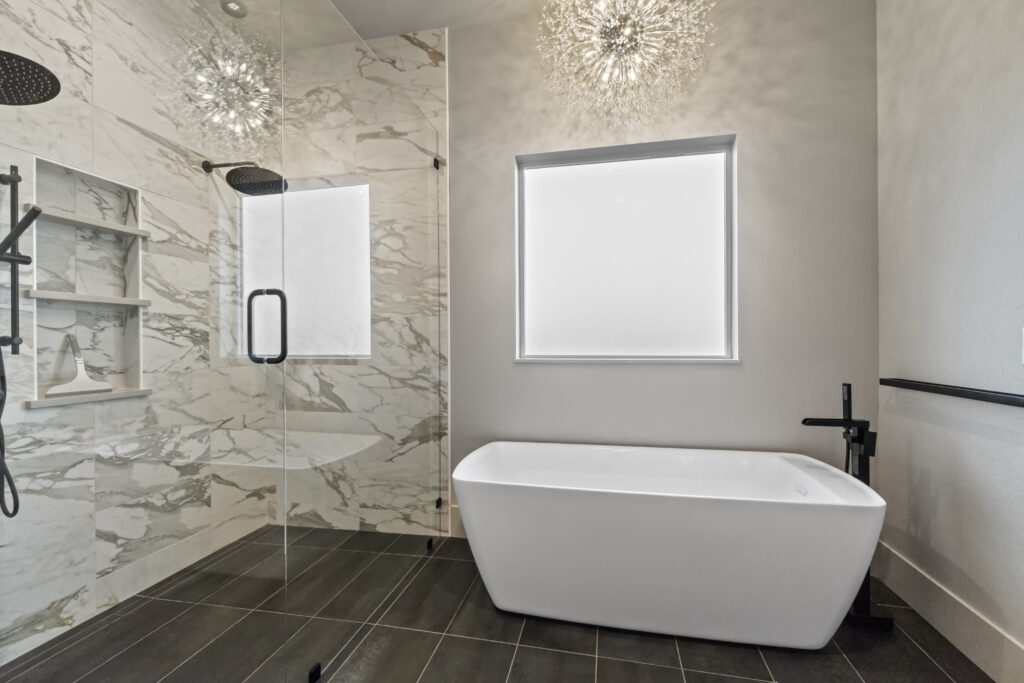 Primary bathroom in The Ascent floor plan with freestanding tub, walk-in shower, marble-look tile, black fixtures, and privacy window.